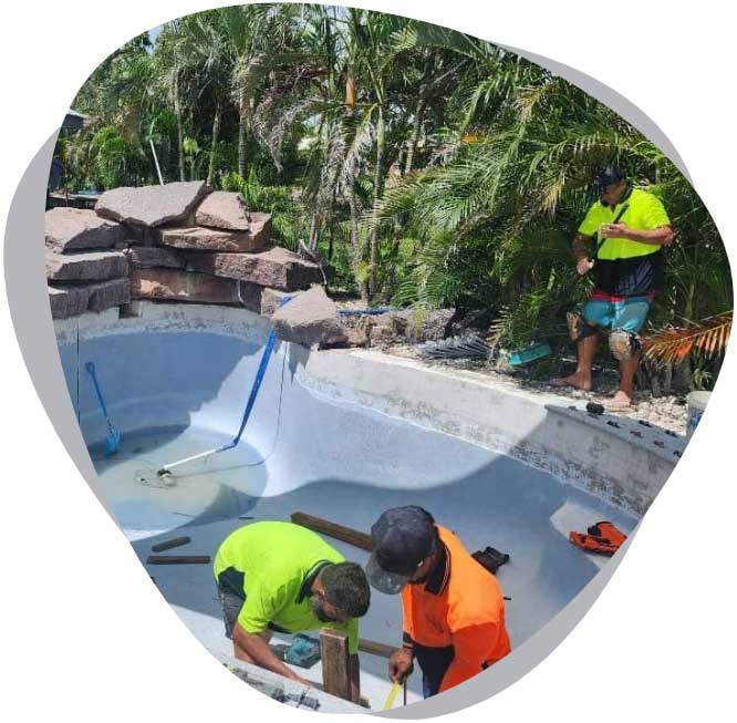 about-img-white-bg Three workers in hi-vis shirts working on an empty pool beside a rock feature