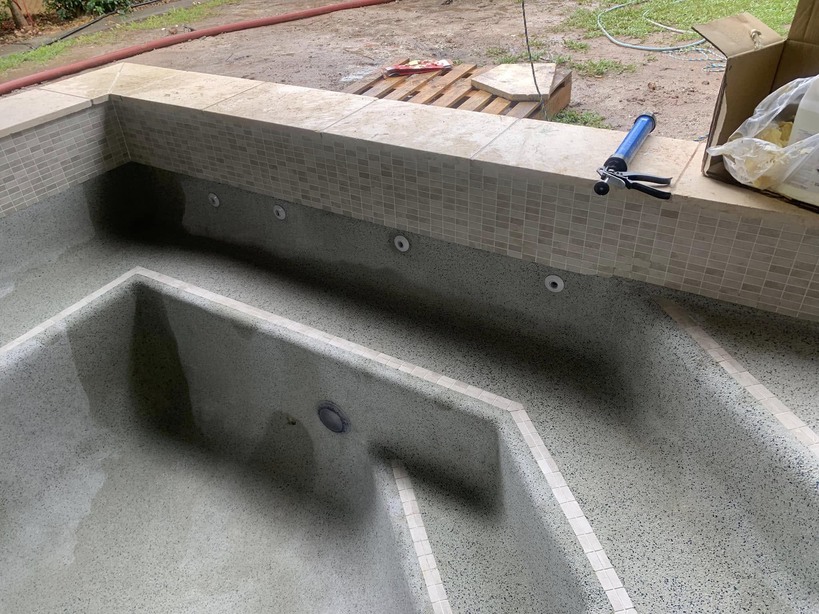 Empty pool with mosaic-tiled walls and a built-in step section, still under construction
