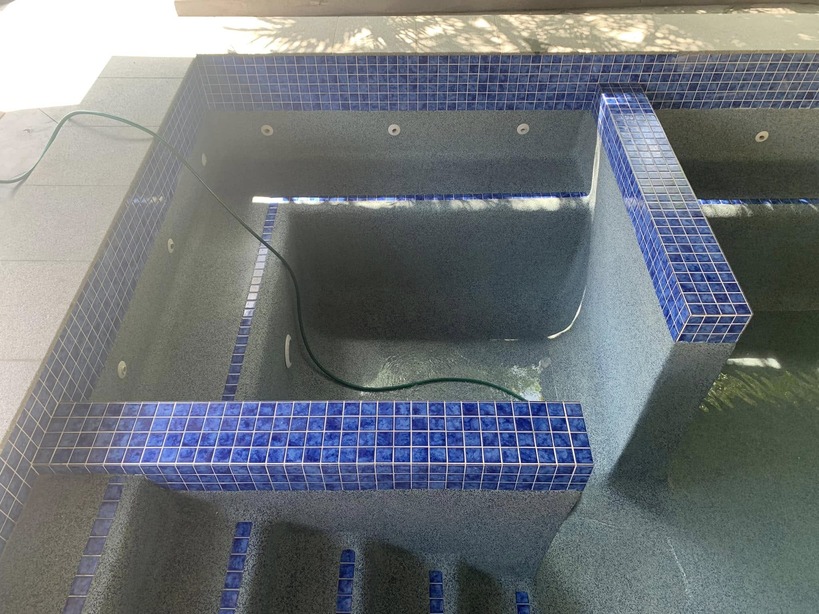 Spa section inside an empty pool edged with blue mosaic tiles