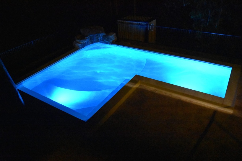 L-shaped pool lit bright blue at night