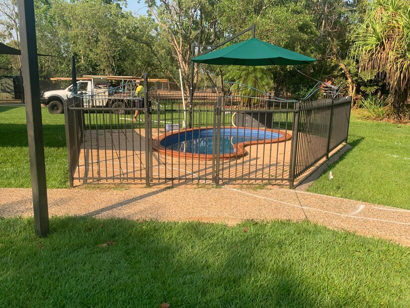 Small fenced pool with a green umbrella in a large grassed backyard