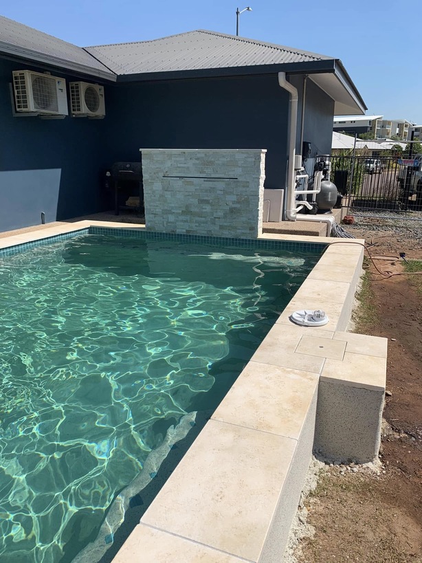 Rectangular pool with sandstone coping and a stone-clad water feature wall