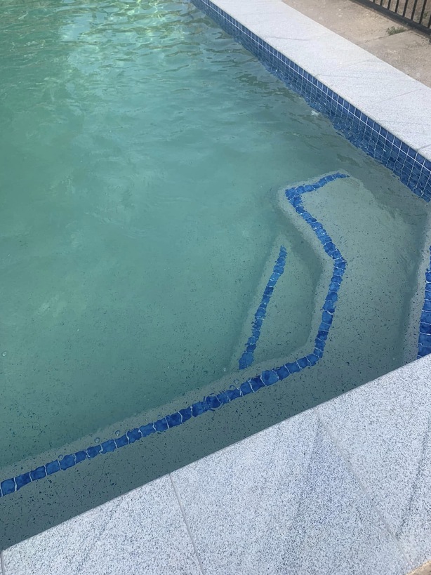 Pool steps edged with blue tiles beside granite coping
