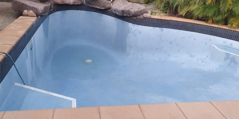 Empty pool with a pale blue interior, dark tile waterline and terracotta coping